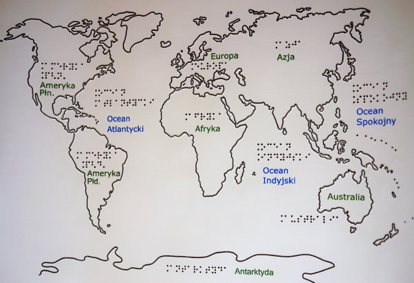 Zdjęcie przedstawia uwypukloną mapę świata z nazwami kontynentów i oceanów w brajlu